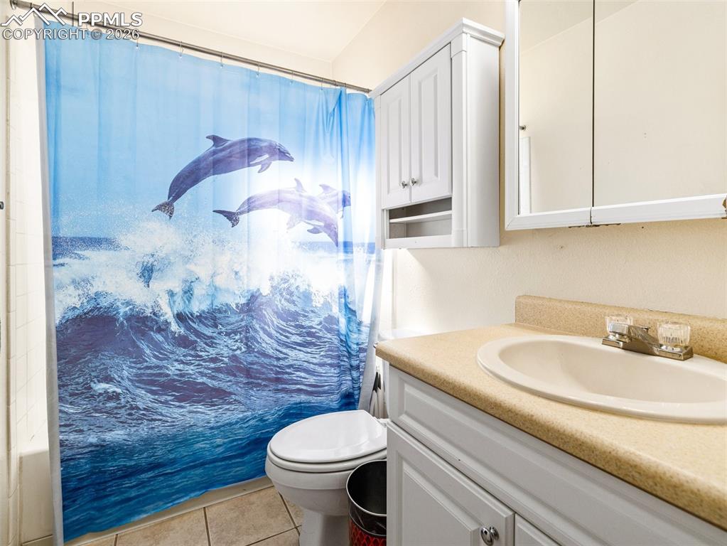 Image 18 of 30: Bathroom featuring vanity, light tile patterned flooring, and a shower with