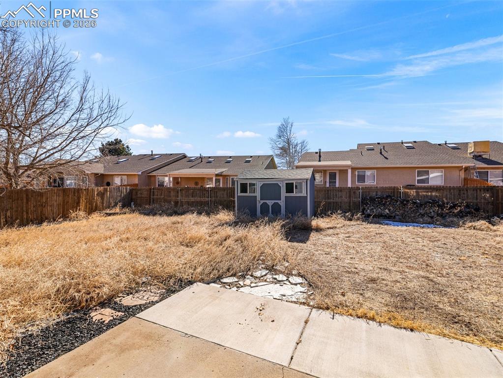 Image 20 of 30: Fenced backyard featuring a residential view and a storage unit