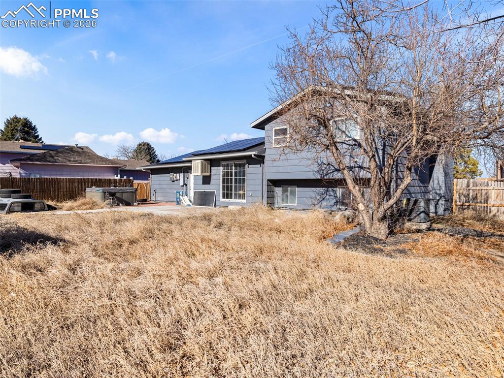 Image 21 of 30: Back of property featuring a fenced backyard, solar panels, and a patio