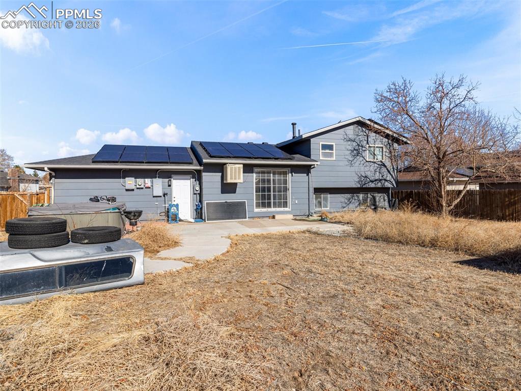 Image 23 of 30: Rear view of house with roof mounted solar panels and a patio area