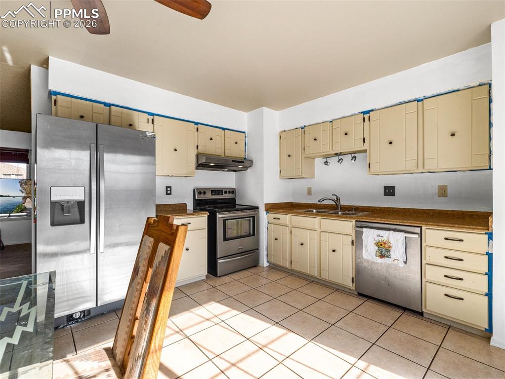 Image 7 of 30: Kitchen with appliances with stainless steel finishes, cream cabinetry, und