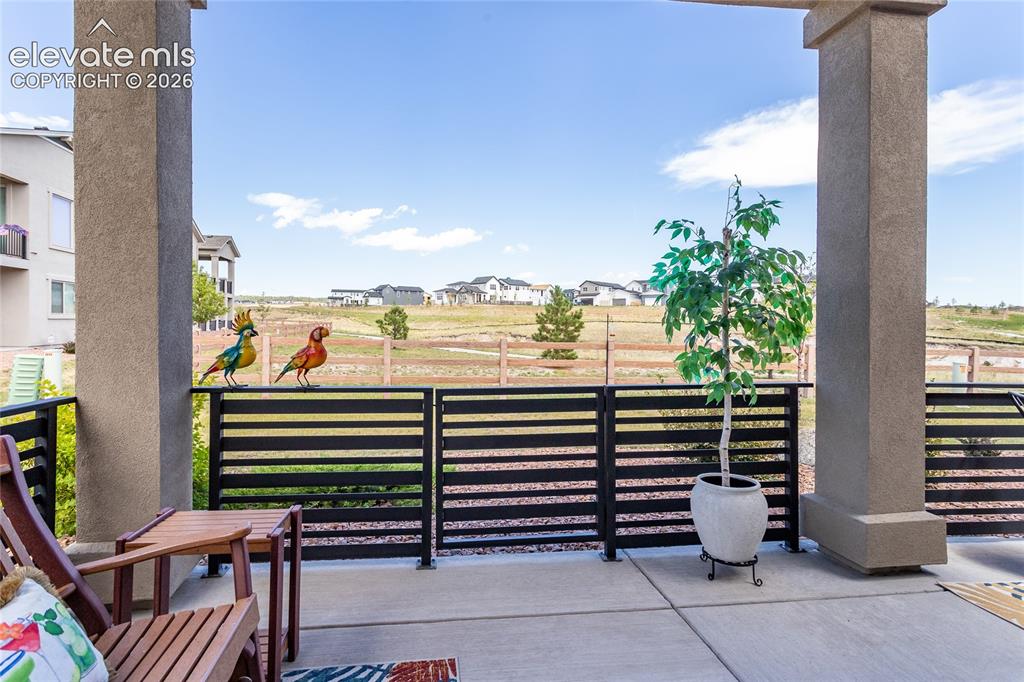 Image 23 of 23: Expansive covered patio with concrete flooring framed by two substantial co
