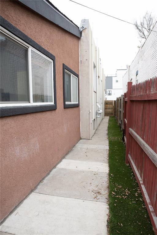 Image 14 of 15: The property features a stucco exterior with white-framed windows, a concre