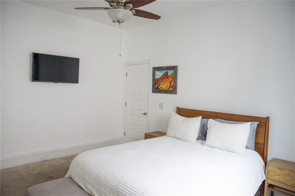 Image 6 of 15: This room features a ceiling fan, white walls, and a door with paneled deta