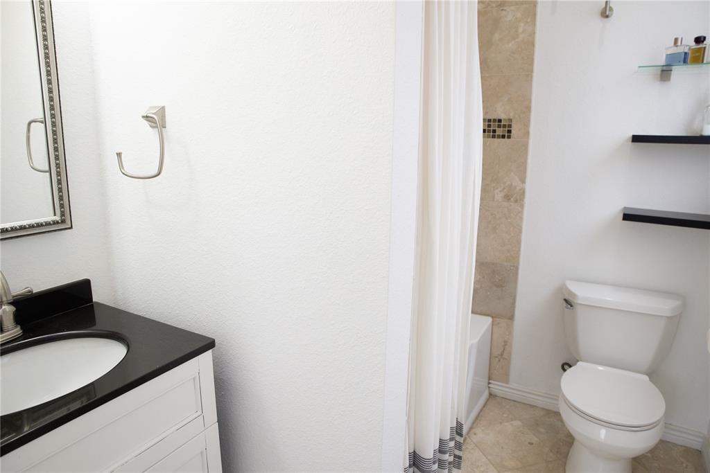 Image 8 of 15: Bathroom featuring a vanity with a dark countertop and undermount sink, a t