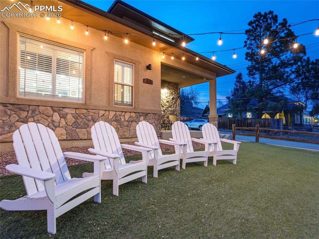 Image 3 of 47: Front yard seating area with Adirondack chairs, café lighting, and low-main