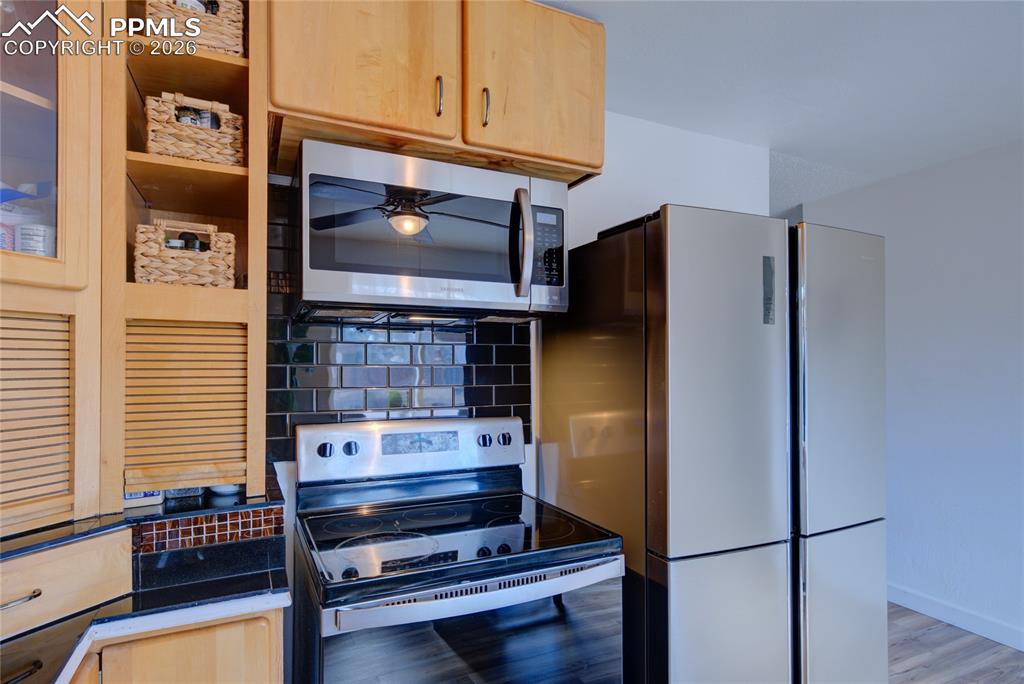 Image 10 of 35: Kitchen with electric range oven, stainless steel microwave, tasteful backs