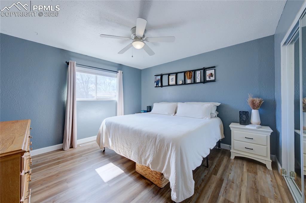 Image 13 of 35: Bedroom featuring light wood-type flooring, ceiling fan, and a textured wal