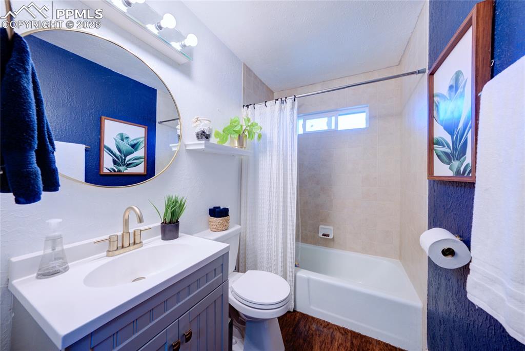 Image 17 of 35: Bathroom with vanity, shower / tub combo with curtain, a textured wall, and