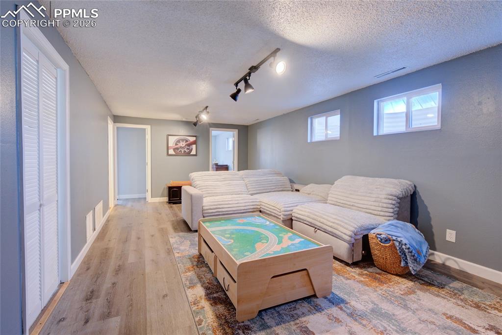 Image 21 of 35: Living room featuring rail lighting, wood finished floors, and a textured c