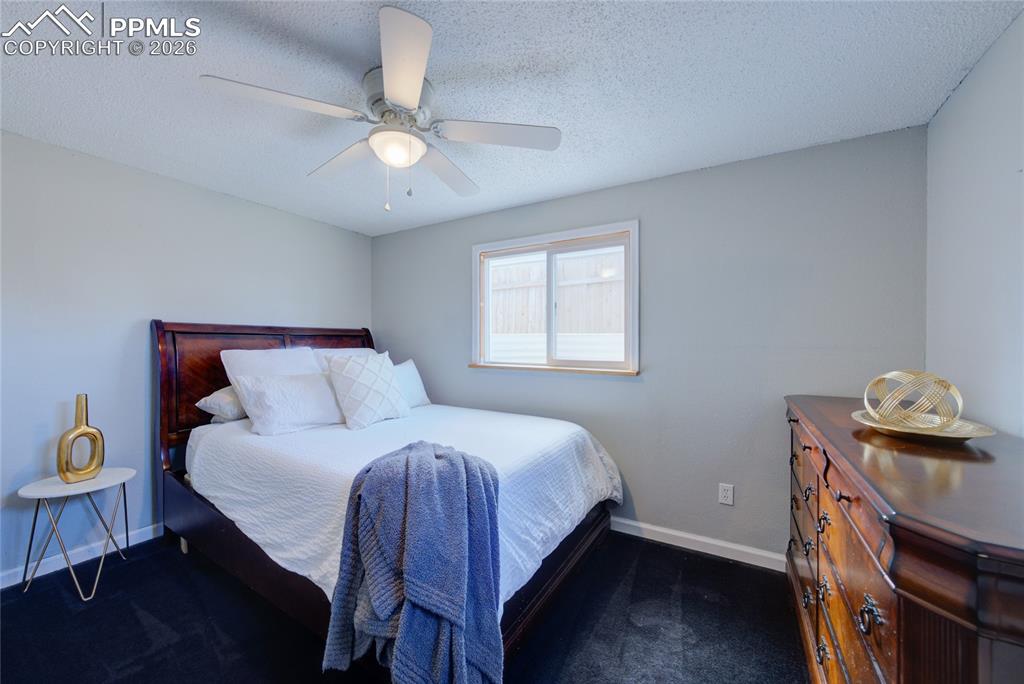 Image 22 of 35: Bedroom with a textured ceiling, ceiling fan, and dark colored carpet