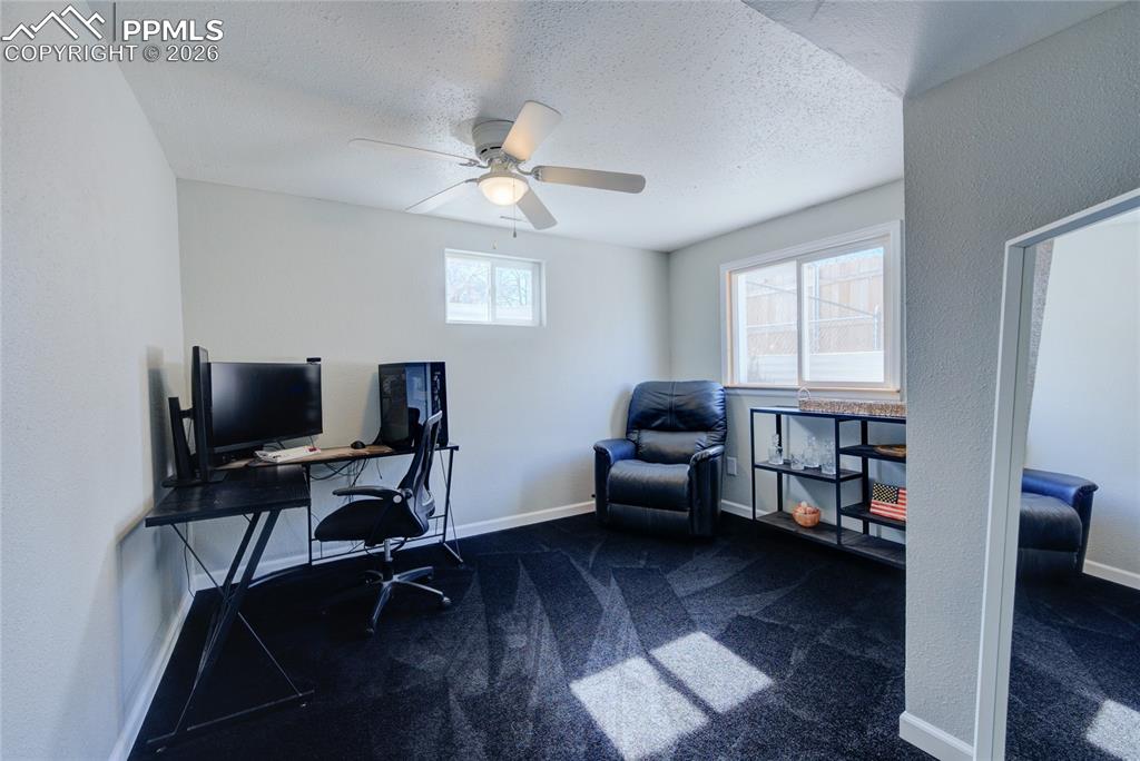 Image 24 of 35: Home office with dark carpet, a textured ceiling, and a ceiling fan