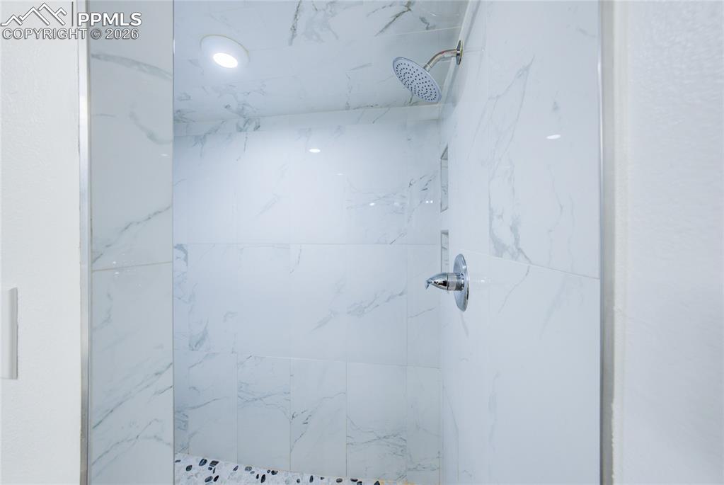 Image 26 of 35: Full bath with a marble finish shower