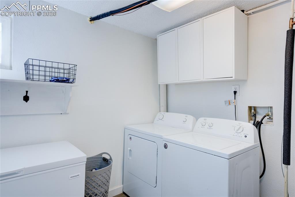 Image 27 of 35: Laundry room featuring independent washer and dryer, cabinet space, and a t