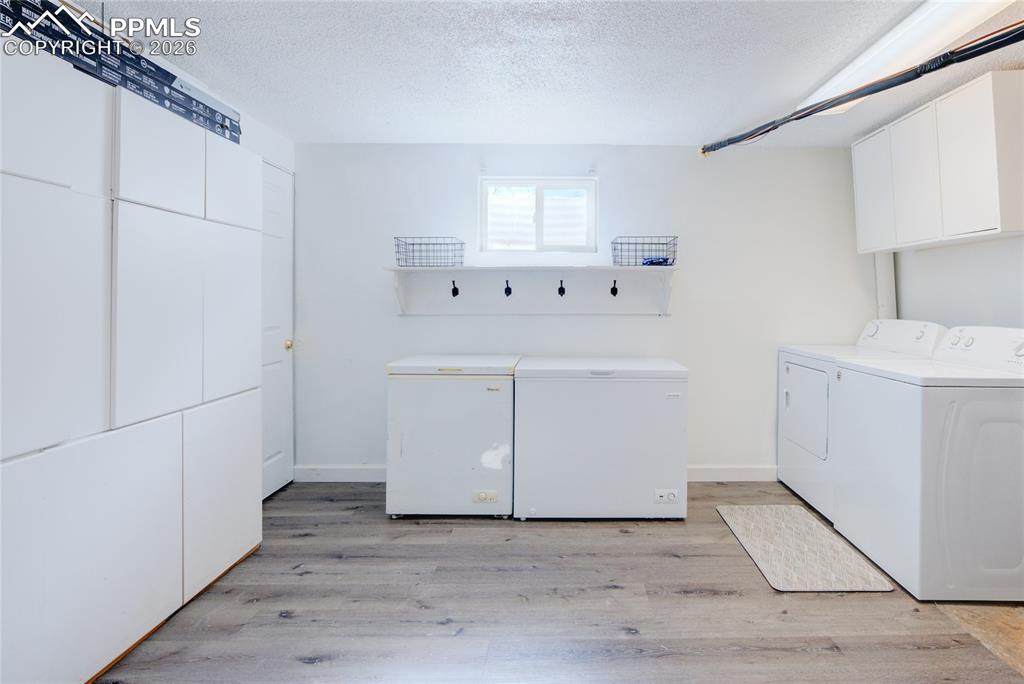 Image 29 of 35: Laundry room featuring a textured ceiling, light wood-style floors, separat