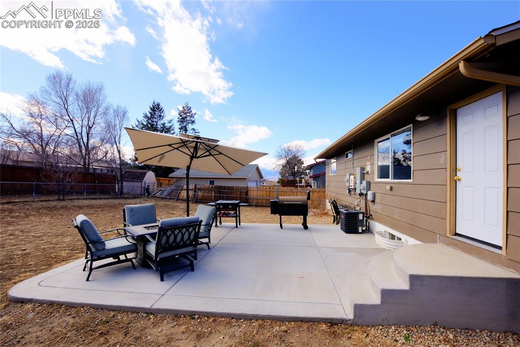 Image 31 of 35: Fenced backyard with a patio, grilling area, and outdoor dining area