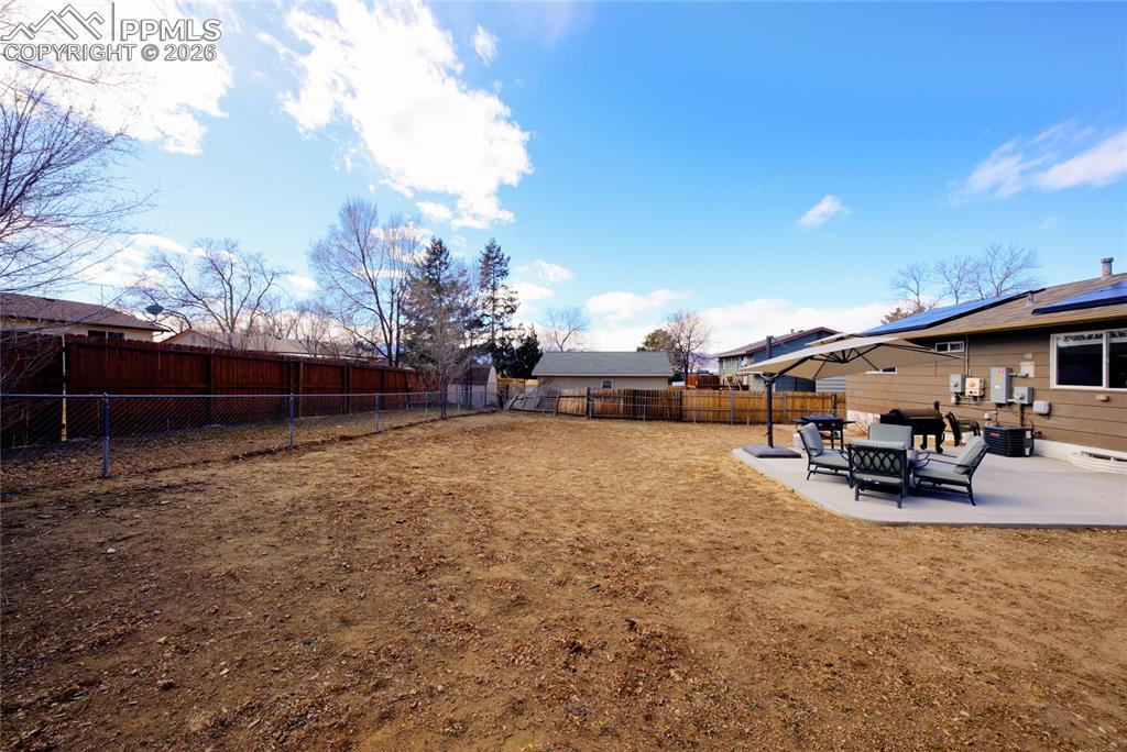 Image 34 of 35: Fenced backyard with a patio