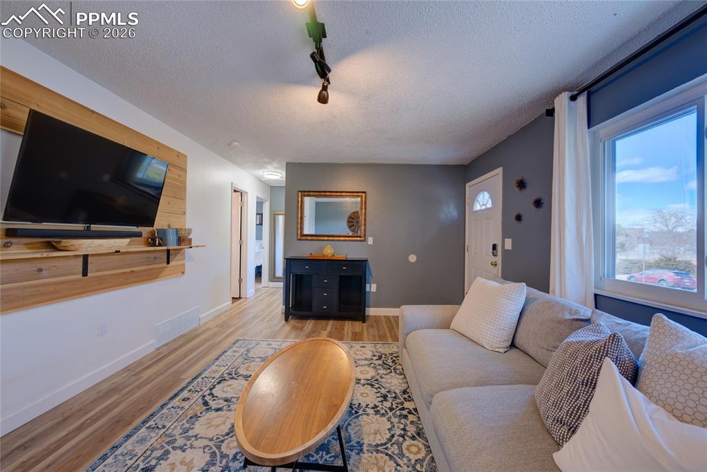 Image 4 of 35: Living room with a textured ceiling, track lighting, and light wood-type fl