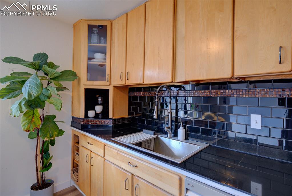 Image 9 of 35: Kitchen featuring backsplash, glass fronted cabinets, light wood finish cab