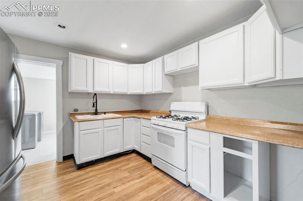 Image 10 of 35: Modern kitchen with white cabinetry, updated appliances, and clean finishes