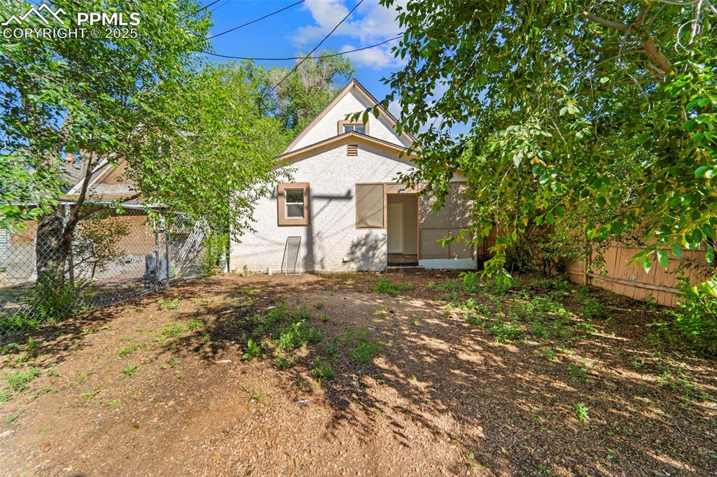 Image 29 of 35: Rear elevation with yard access and mature trees.