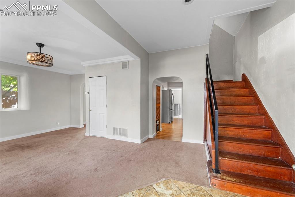 Image 5 of 35: Open-concept living space featuring a charming staircase and natural light.
