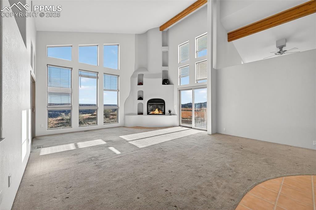 Image 11 of 50: living room with carpet, a glass covered fireplace, high vaulted ceiling, a