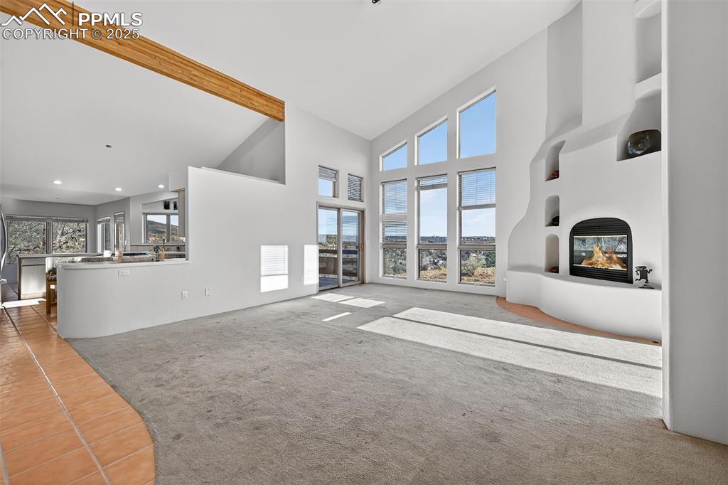 Image 12 of 50: living room with a glass covered fireplace, carpeted floors, high vaulted c