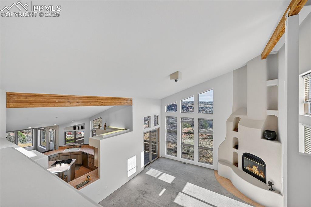 Image 32 of 50: Living room featuring beamed ceiling, a glass covered fireplace, and high v