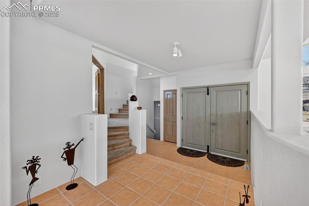 Image 6 of 50: Foyer with stairs, light tile patterned flooring, and recessed lighting