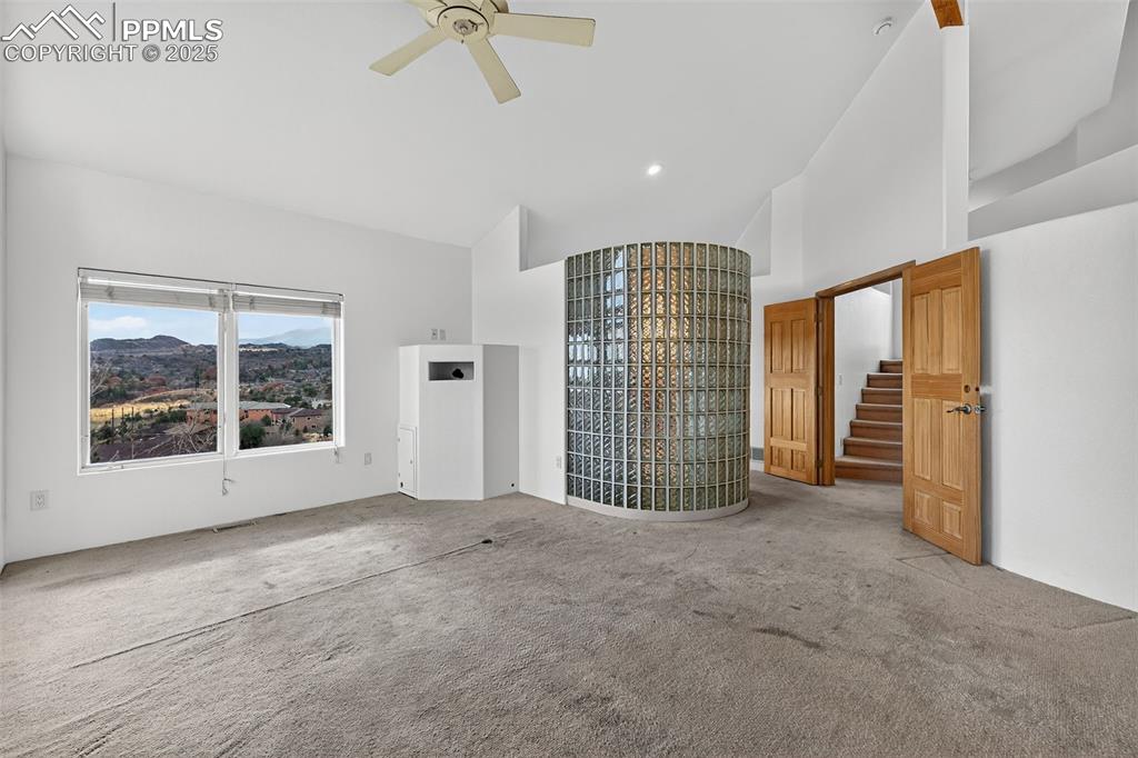 Image 9 of 50: primary bedroom with carpet, high vaulted ceiling, and ceiling fan