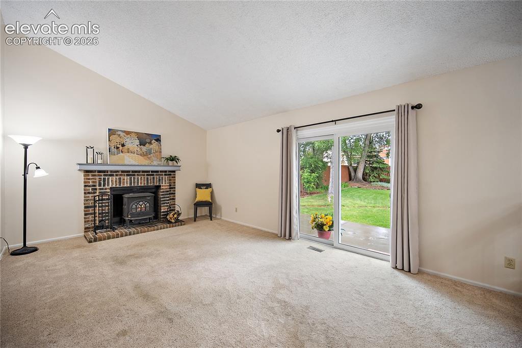 Image 17 of 42: Family room features carpet. Fireplace and walks out to back yard. 