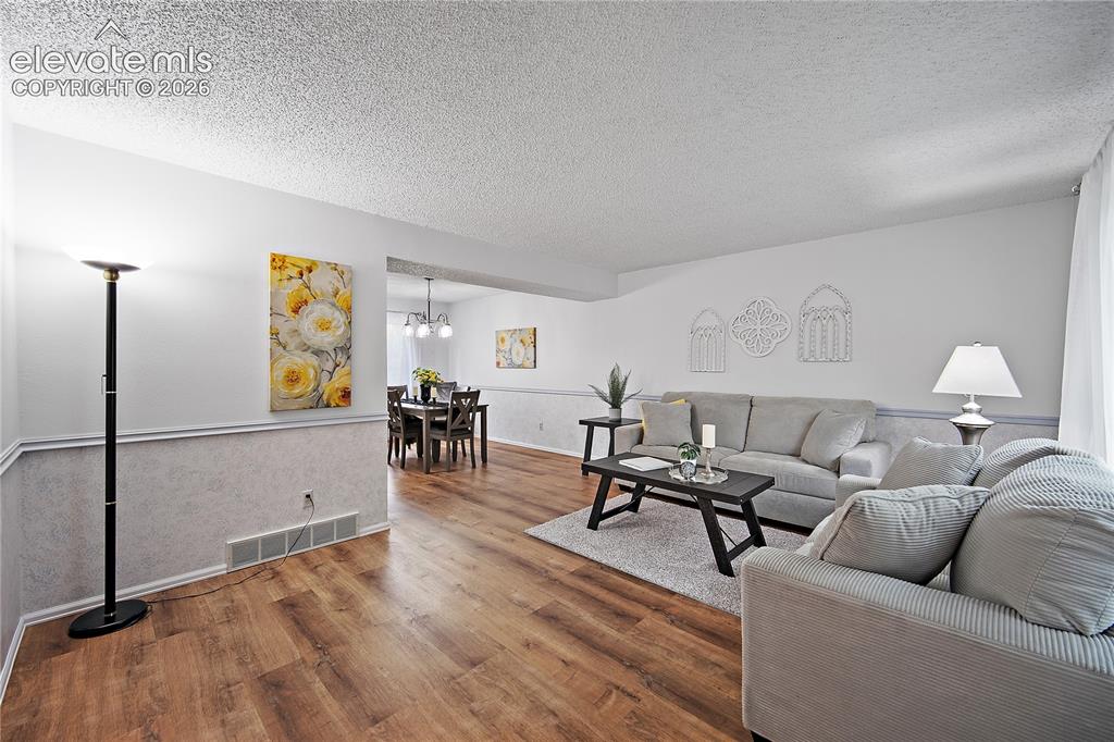 Image 6 of 42: Formal living room with laminate flooring, open to the formal dining room. 