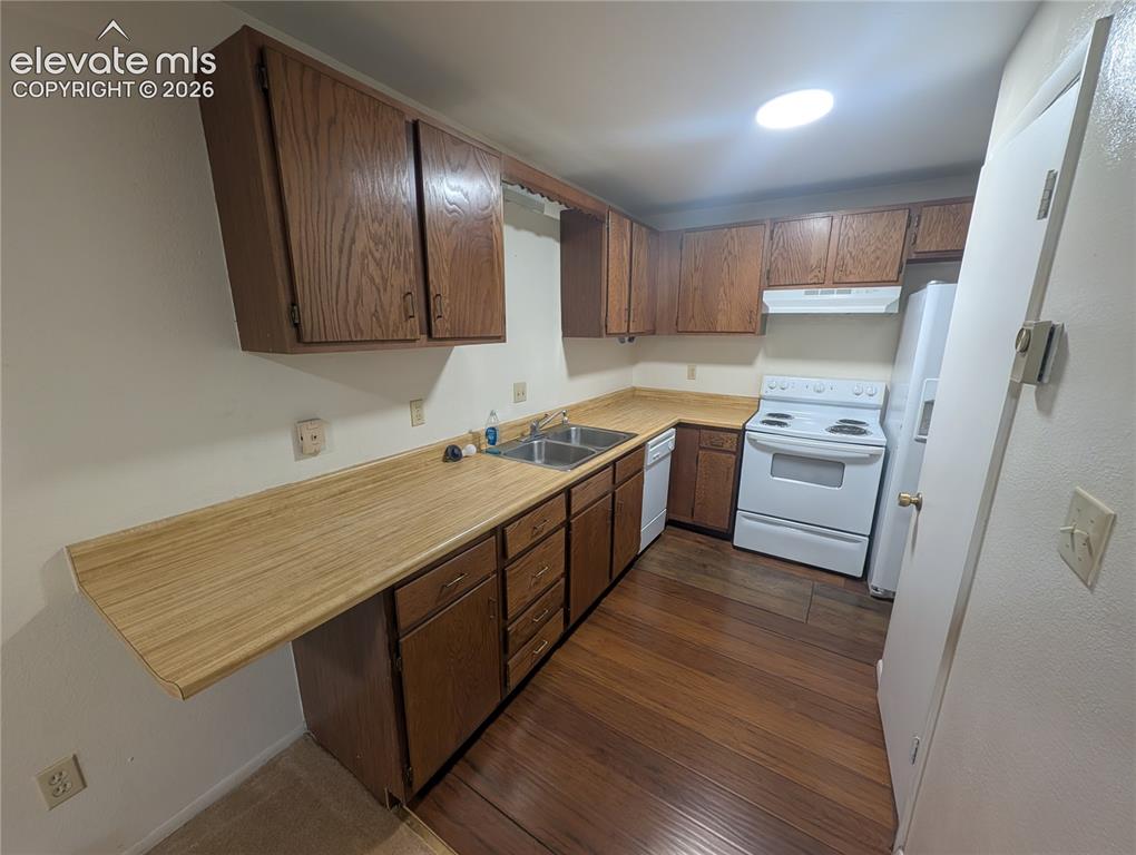 Image 14 of 30: Kitchen featuring wood-finish flooring, wood cabinetry, white appliances, a