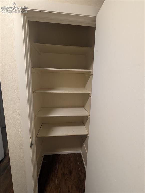 Image 15 of 30: Built-in shelving with multiple levels, wood-finish flooring, and a white d