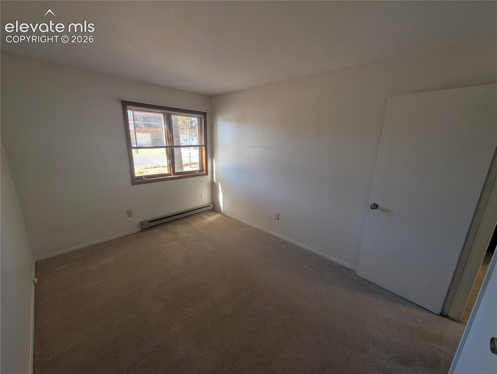 Image 20 of 30: Carpeted flooring, white walls, and a window with wood-finish trim