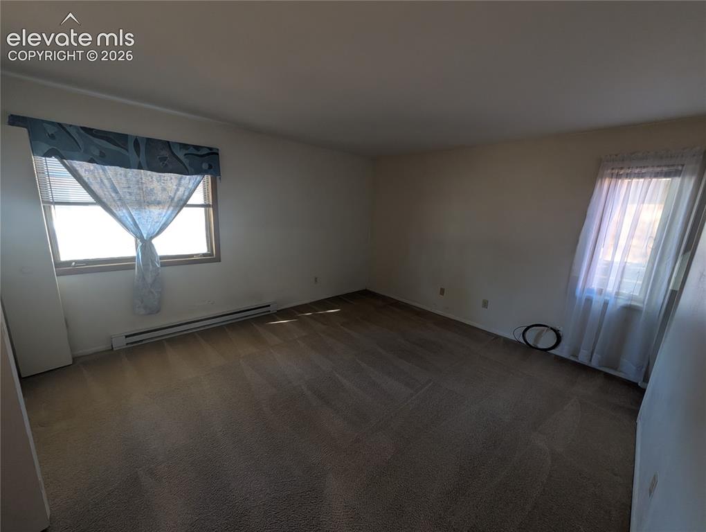 Image 23 of 30: Carpeted interior space with multiple windows and baseboard heating