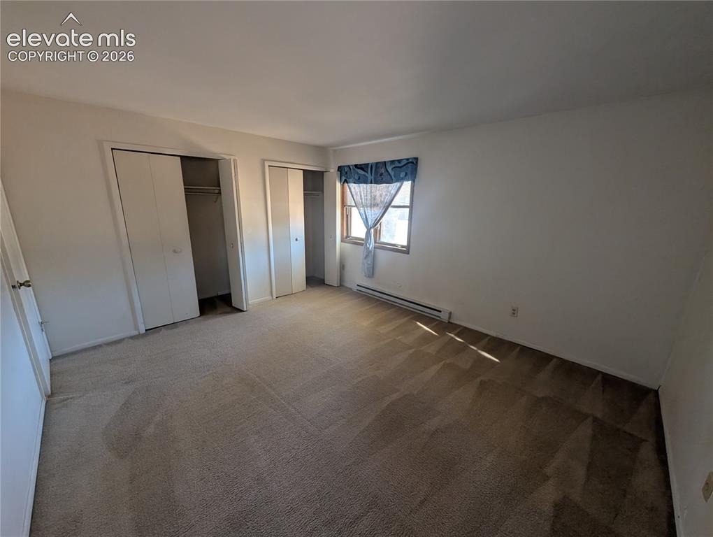 Image 24 of 30: Spacious bedroom featuring neutral carpeting, dual closets with sliding doo