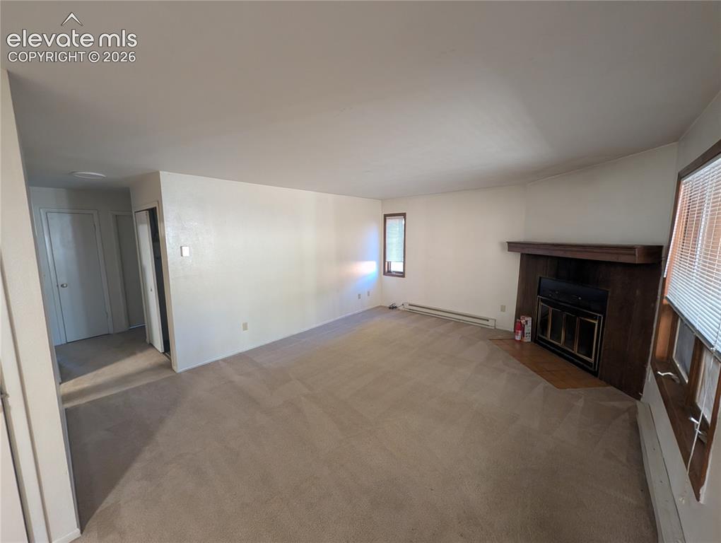 Image 8 of 30: Expansive living area featuring neutral carpeting, a built-in fireplace wit