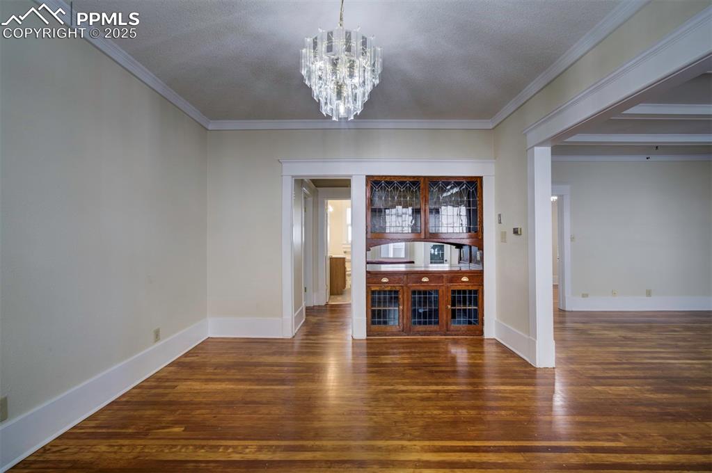 Image 12 of 40: Unfurnished dining area featuring dark wood-type flooring, a chandelier, cr