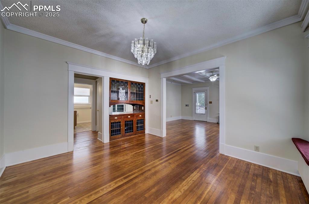 Image 14 of 40: Unfurnished dining area featuring dark wood-style flooring, a chandelier, a