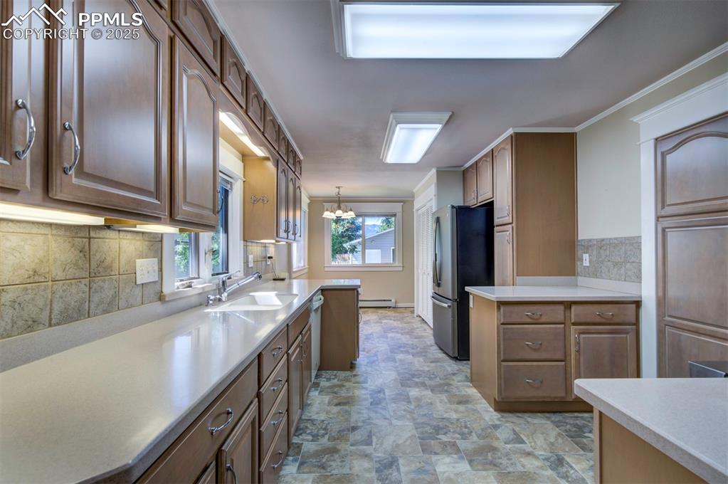 Image 17 of 40: Kitchen with backsplash, decorative light fixtures, freestanding refrigerat