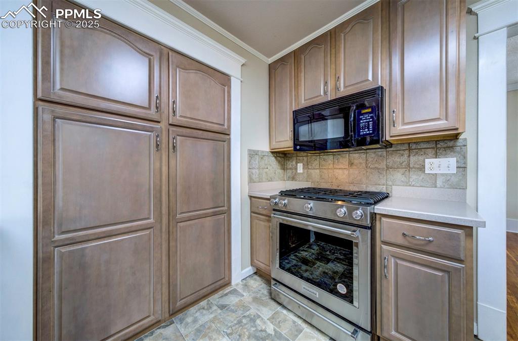 Image 20 of 40: Kitchen with stainless steel gas range oven, tasteful backsplash, black mic