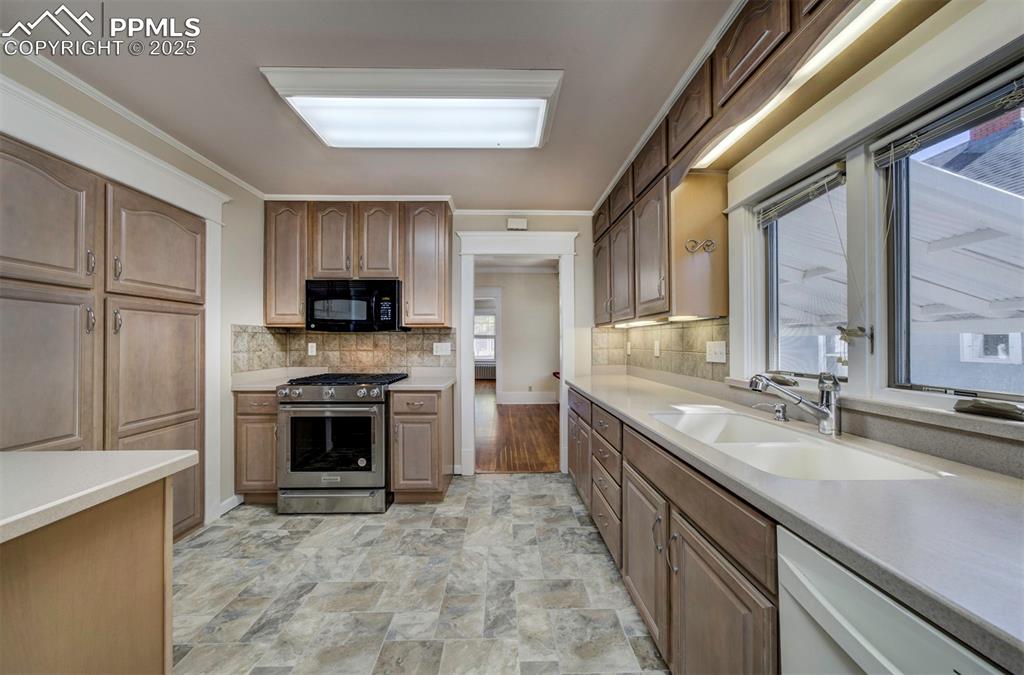 Image 21 of 40: Kitchen with stainless steel gas stove, tasteful backsplash, black microwav