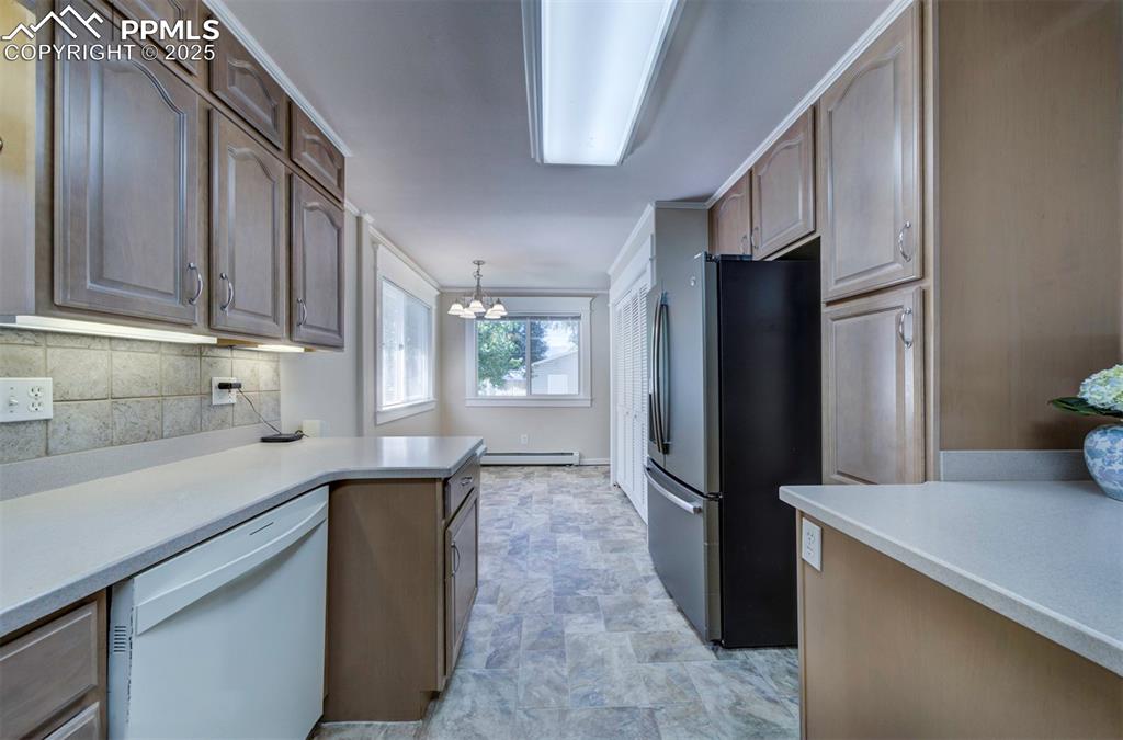 Image 22 of 40: Kitchen with freestanding refrigerator, white dishwasher, pendant lighting,