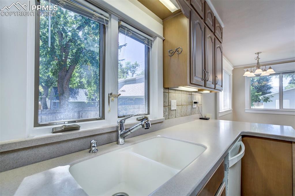 Image 23 of 40: Kitchen with light stone countertops, hanging light fixtures, a chandelier,