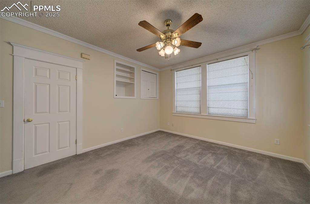 Image 27 of 40: Carpeted spare room with crown molding, a textured ceiling, and ceiling fan