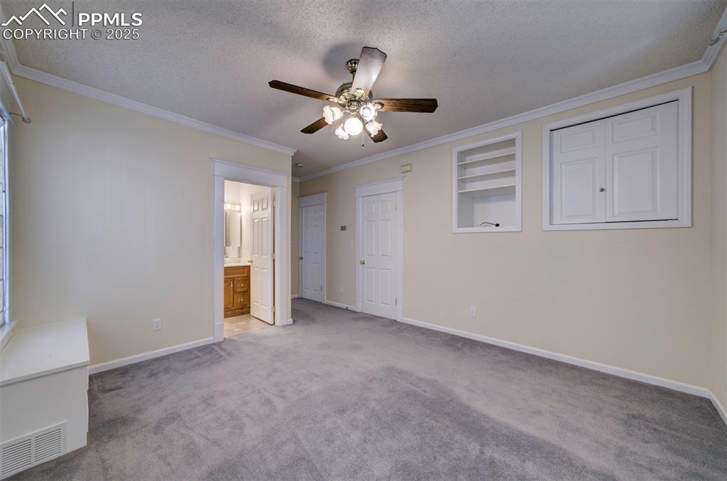 Image 28 of 40: Unfurnished bedroom with crown molding, carpet floors, a textured ceiling, 