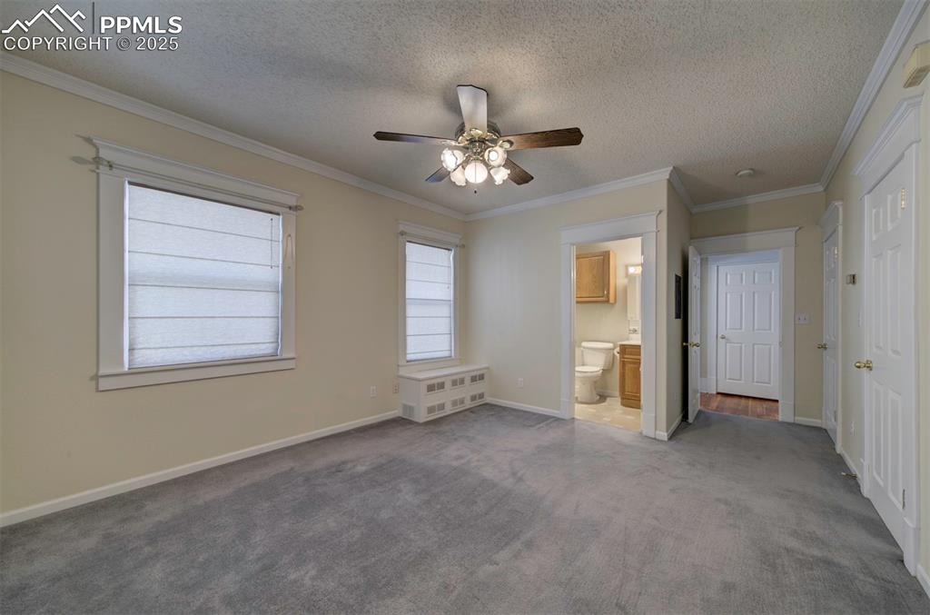 Image 29 of 40: bedroom with carpet, ornamental molding, a textured ceiling, a ceiling fan,