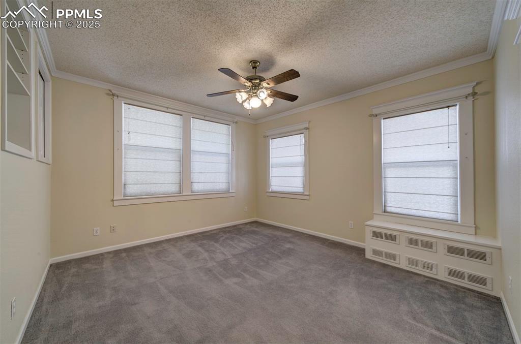 Image 30 of 40: Empty room featuring crown molding, a textured ceiling, dark carpet, and a 
